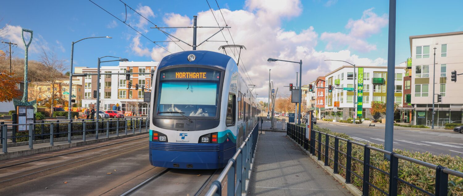 Light rail train at the Columbia City station, flanked by apartment buildings on both sides